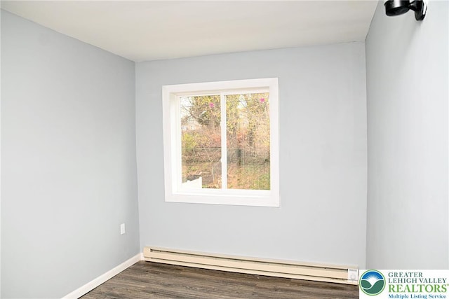 unfurnished room featuring baseboard heating, baseboards, and dark wood-type flooring