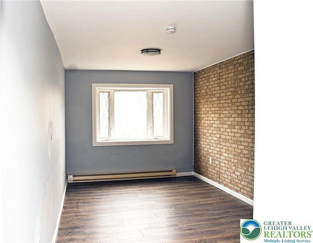 spare room with dark wood finished floors, brick wall, a baseboard heating unit, and baseboards
