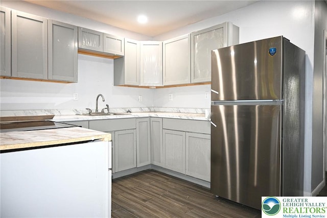kitchen with a sink, light countertops, dark wood-style floors, freestanding refrigerator, and gray cabinets