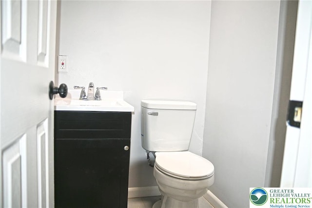 half bath with baseboards, toilet, tile patterned flooring, and vanity