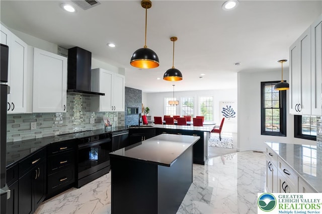 kitchen featuring wall chimney range hood, a peninsula, recessed lighting, and backsplash
