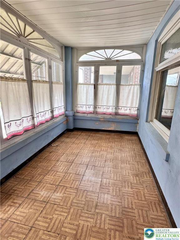 unfurnished sunroom with wood ceiling and baseboards
