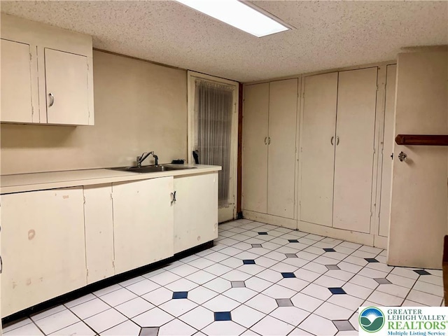 kitchen with light floors, a sink, white cabinets, and light countertops