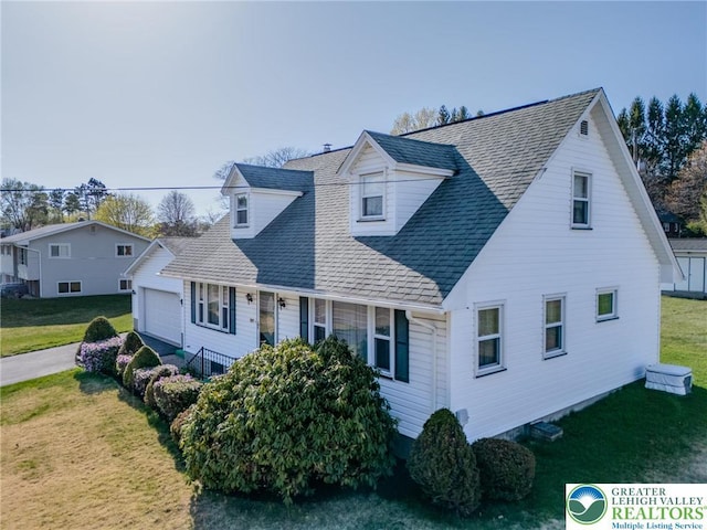 view of front of property with roof with shingles, a front lawn, and a garage