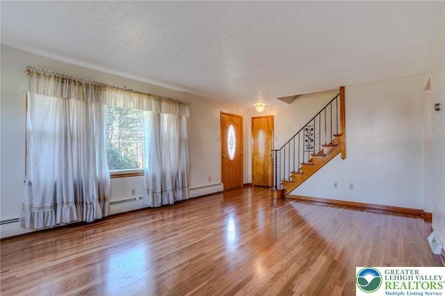 foyer featuring wood finished floors, baseboards, a baseboard heating unit, and stairs