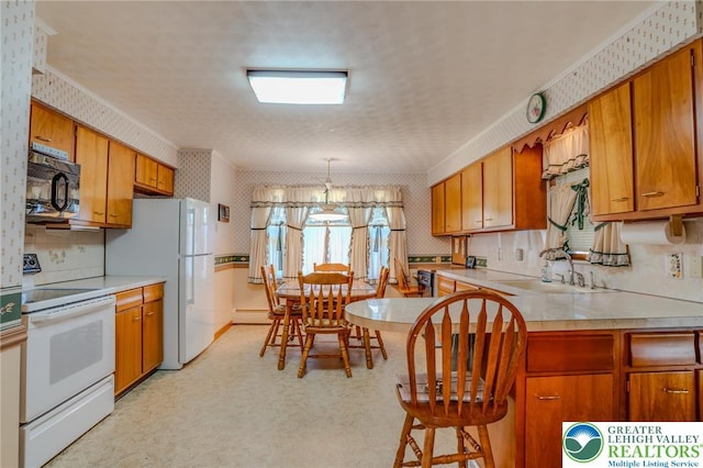 kitchen with brown cabinets, wallpapered walls, and white appliances