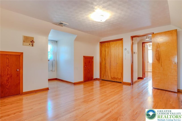 unfurnished room featuring light wood finished floors, visible vents, baseboards, and a healthy amount of sunlight