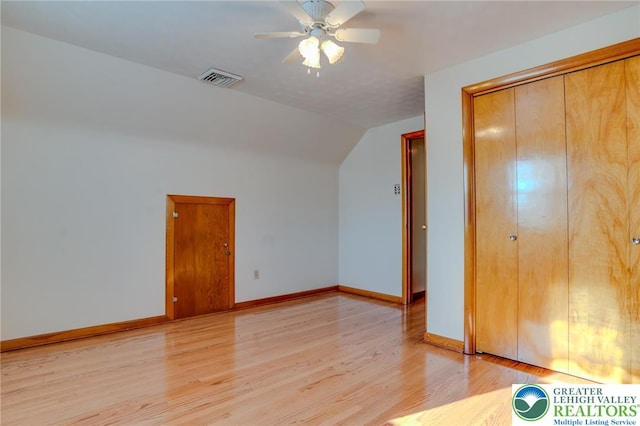 unfurnished bedroom with a closet, light wood-type flooring, visible vents, baseboards, and lofted ceiling