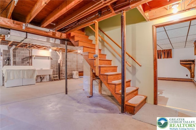 unfinished basement featuring stairs and a sink