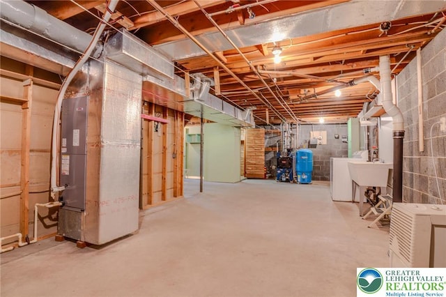 unfinished below grade area with washing machine and dryer, heating unit, and a sink