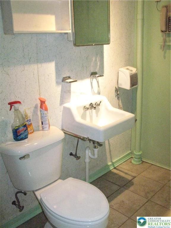 bathroom with tile patterned flooring, baseboards, and toilet
