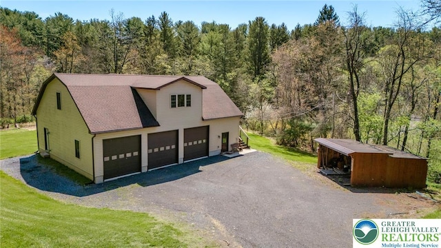 garage featuring a view of trees and driveway