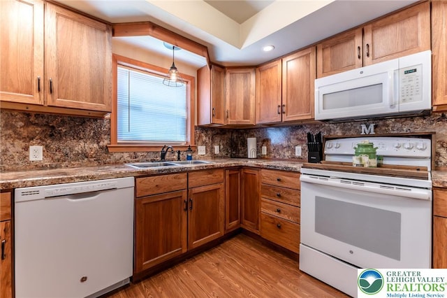 kitchen featuring a sink, backsplash, white appliances, and light wood-style flooring