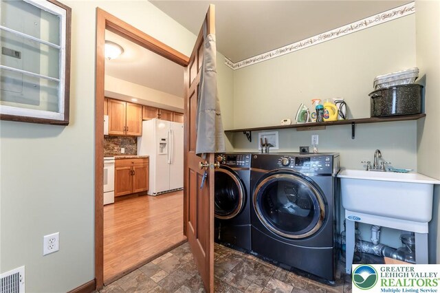 laundry area featuring laundry area, washing machine and dryer, stone finish floor, and visible vents