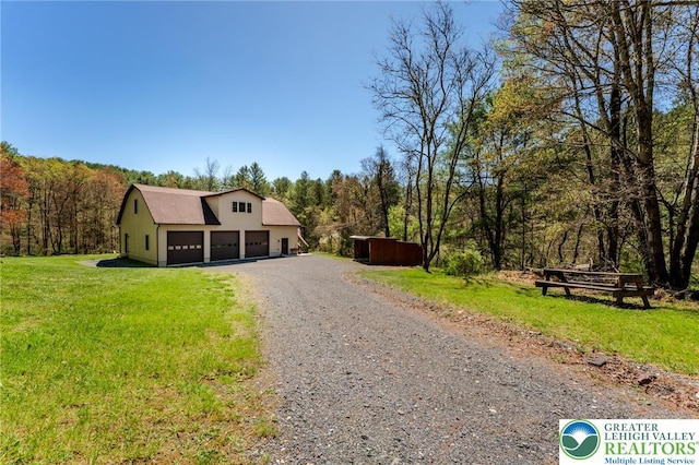 view of front of home with a garage, a front lawn, driveway, and a view of trees