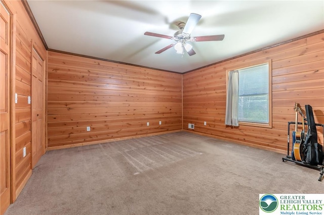 interior space with carpet flooring, ceiling fan, and wooden walls