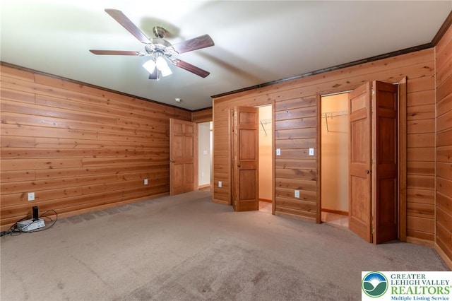 unfurnished bedroom featuring wood walls, carpet, and ceiling fan