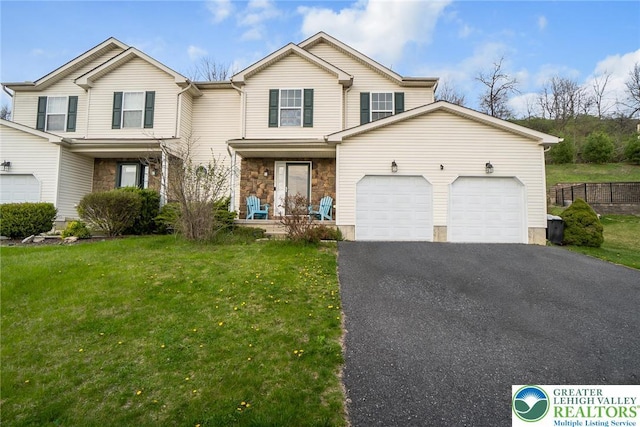 traditional home featuring covered porch, a front yard, stone siding, an attached garage, and driveway
