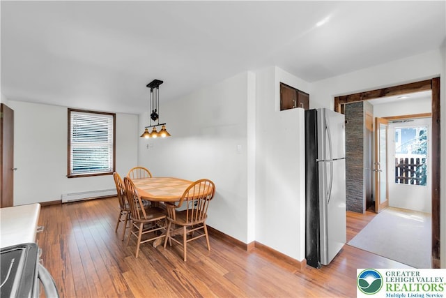 dining room featuring baseboards, a baseboard heating unit, and light wood-style flooring