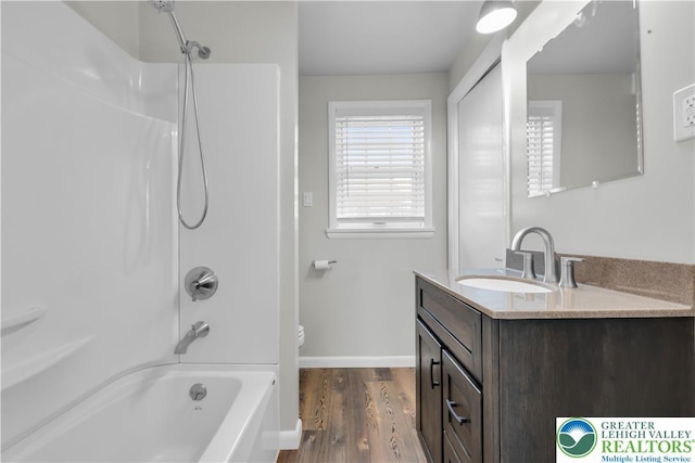 bathroom featuring vanity, wood finished floors, toilet, baseboards, and  shower combination