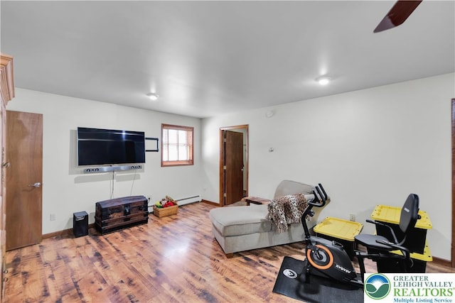 living area featuring baseboard heating, baseboards, a ceiling fan, and wood finished floors