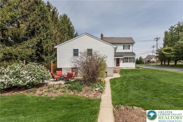view of front of property with a chimney, a front yard, and entry steps
