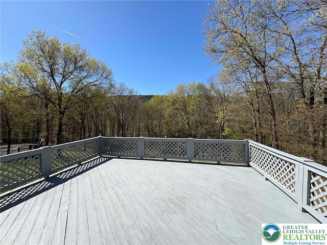 wooden terrace featuring a view of trees