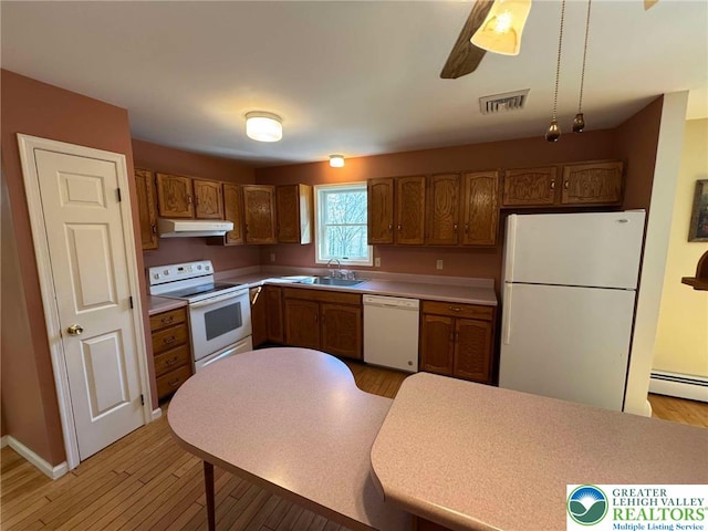 kitchen featuring a sink, light wood finished floors, white appliances, under cabinet range hood, and visible vents