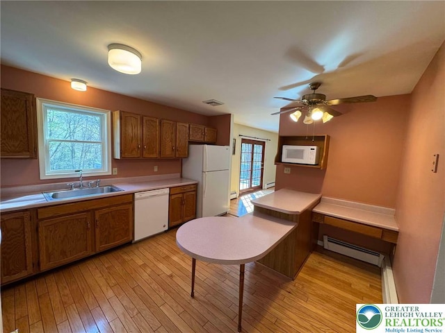 kitchen featuring visible vents, white appliances, baseboard heating, brown cabinets, and a sink
