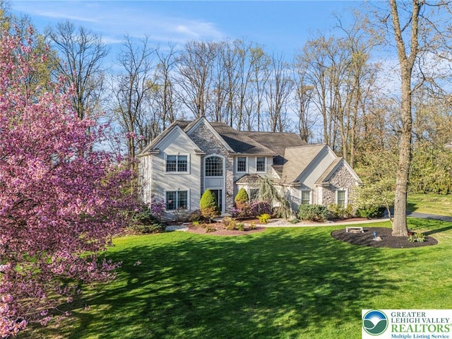 traditional home featuring a front yard and stone siding