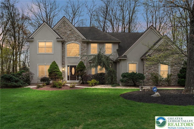 traditional home with a front lawn, stucco siding, and stone siding
