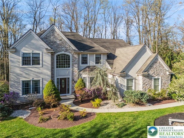 view of front of home featuring a front yard, stone siding, and stucco siding