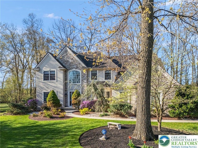 traditional-style house with stone siding and a front yard