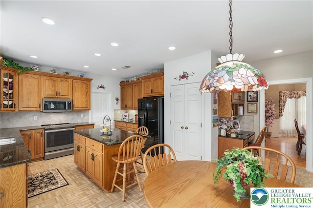 kitchen featuring glass insert cabinets, tasteful backsplash, a kitchen island, and stainless steel appliances