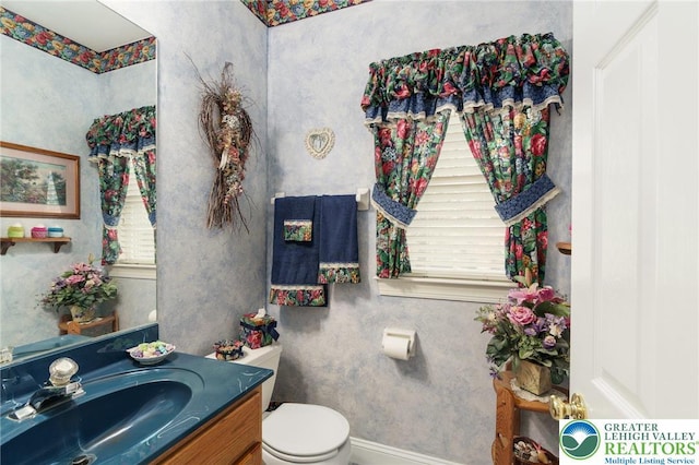 half bath with vanity, baseboards, and toilet