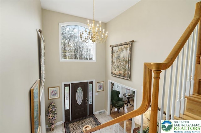 tiled entrance foyer featuring baseboards, a chandelier, stairway, and a towering ceiling