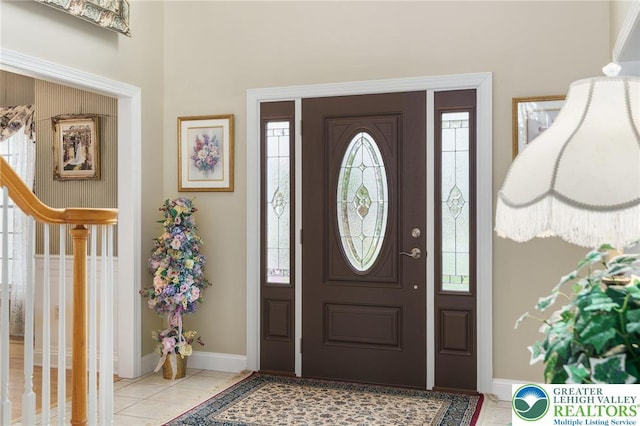tiled foyer entrance with baseboards, a high ceiling, and a wealth of natural light