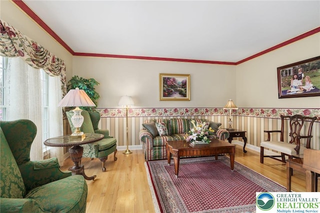 living room with ornamental molding, wood finished floors, and a wainscoted wall