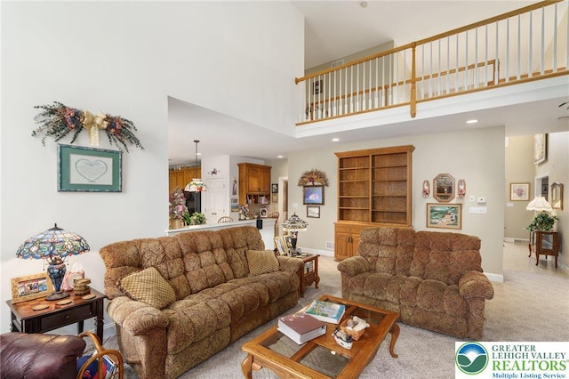 living room with recessed lighting, a high ceiling, light colored carpet, and baseboards