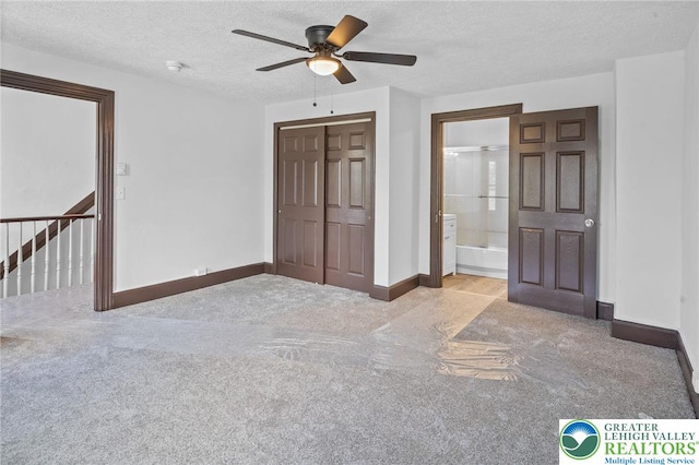 unfurnished bedroom with carpet flooring, a textured ceiling, baseboards, and a closet