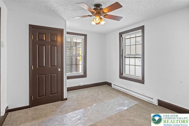 empty room with carpet floors, a textured ceiling, ceiling fan, and baseboard heating