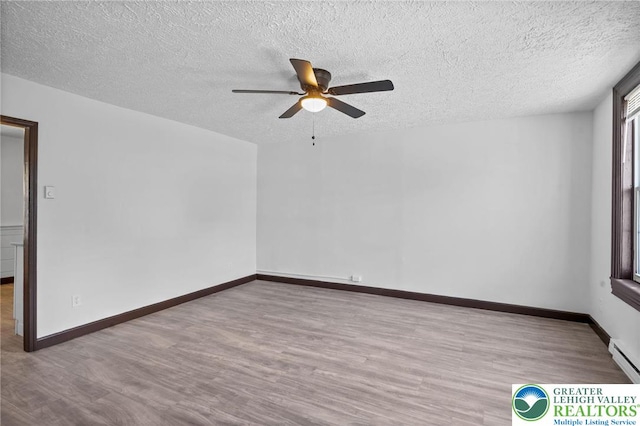 empty room with a textured ceiling, baseboards, a ceiling fan, and wood finished floors