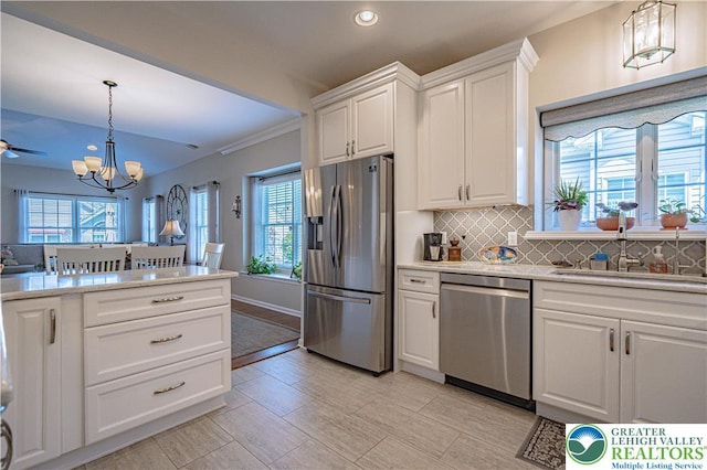 kitchen featuring light countertops, appliances with stainless steel finishes, an inviting chandelier, and plenty of natural light