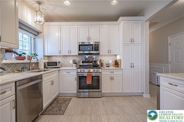 kitchen featuring backsplash, a sink, white cabinets, stainless steel appliances, and recessed lighting