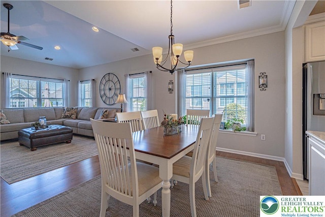 dining area with baseboards, visible vents, wood finished floors, and ceiling fan with notable chandelier
