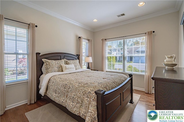 bedroom with crown molding, light wood-style floors, recessed lighting, baseboards, and visible vents