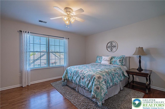 bedroom featuring visible vents, baseboards, ceiling fan, and wood finished floors