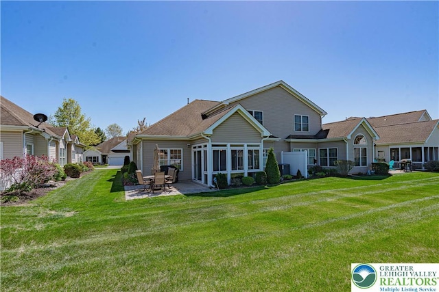 rear view of house featuring a lawn, a sunroom, and a patio area