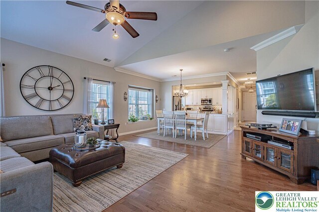 living room featuring visible vents, crown molding, wood finished floors, high vaulted ceiling, and ceiling fan with notable chandelier