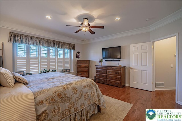 bedroom with baseboards, ornamental molding, wood finished floors, and visible vents